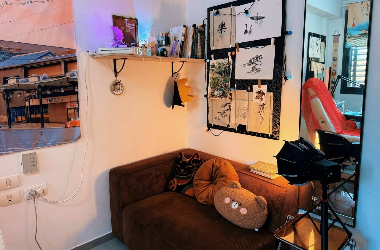 A sofa corner with a shelf, hanging ink drawings and a tall mirror